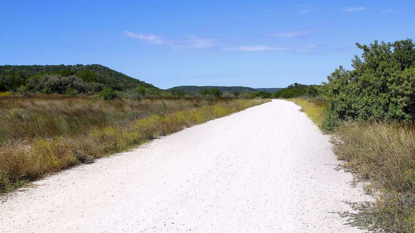 Looking out into Hill Country State Natural Area in Bandera County, Texas, United States. The roads in the park are unpaved.